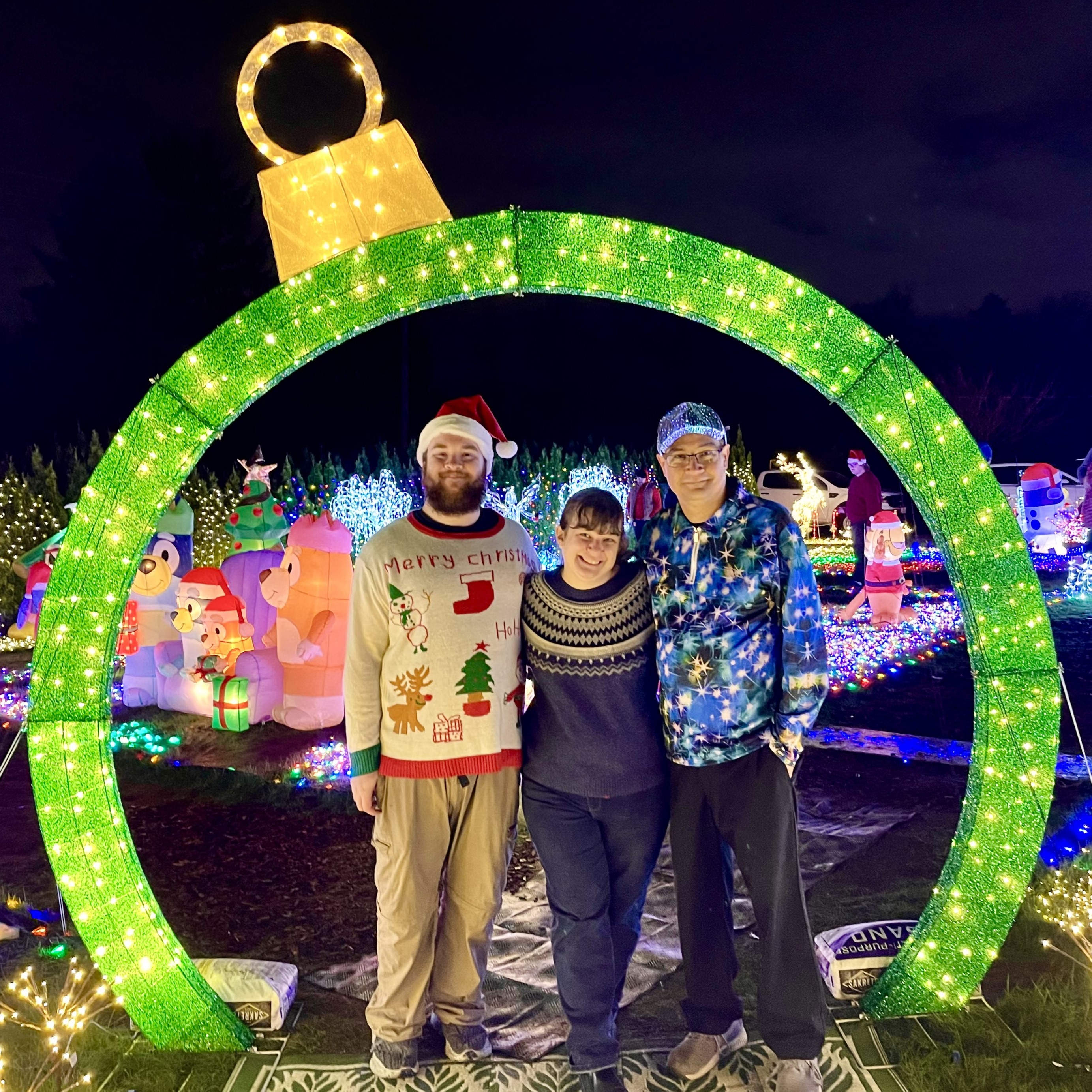 David, Joi, and Levi posing under a Christmas light archway